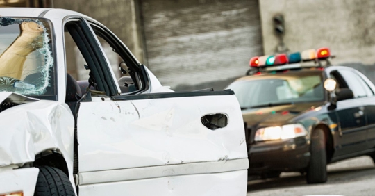Police officer vehicle with its lights flashing behind a different vehicle that was in an accident